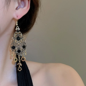 Dettaglio di orecchini vintage dorati con strass neri indossati su una modella
