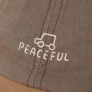 Close-up of PEACEFUL embroidery and car pattern on canvas baseball cap fabric