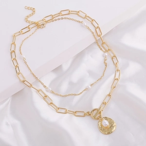 Detail of layered gold paperclip chain and delicate pearl necklace with OT clasp and pendant
