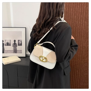 Detailed view of white leather and straw patchwork handbag with gold V-shaped metal lock
