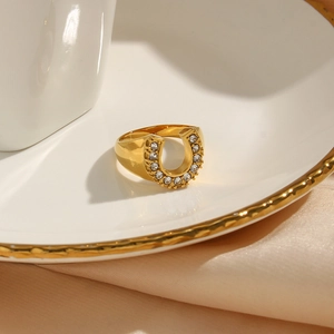 Macro detail of U-shaped gold plated ring with sparkling cubic zirconia on ceramic dish