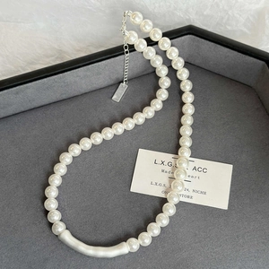 Detail of pearl necklace with matte silver tube on a luxury grey velvet jewelry tray