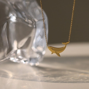 Detail of 18K gold whale pendant necklace showing fine lines and minimalist ocean design