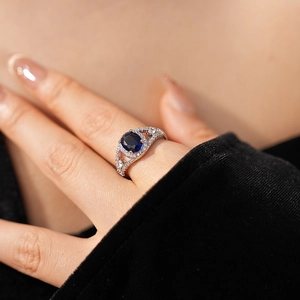 Detail of oval blue zircon ring with hollow diamond-set band on a female hand