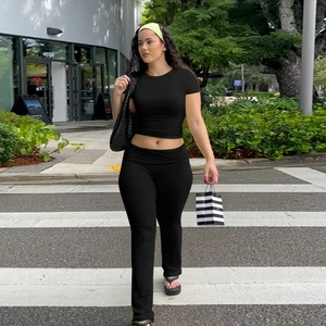 Vista in strada di un completo nero a due pezzi con crop top e pantaloni a vita alta