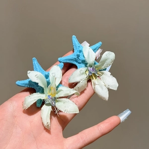Nahaufnahme von floralen Seestern-Haarspangen mit Wassertropfen und mintgrünen Blüten.