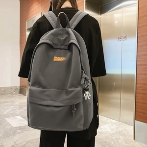 Rear view of a grey large capacity backpack with an astronaut charm for students