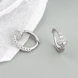 Macro shot of silver snake-shaped earrings with white zircon stones on a gray backdrop
