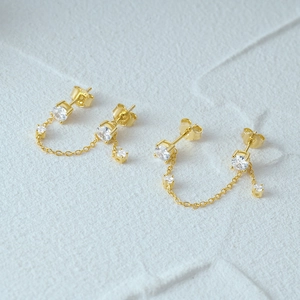 Detailed macro view of 925 sterling silver gold fringe chain earrings with cubic zirconia