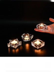 Macro detail of glass candle holders in star, heart, and geometric shapes with warm tealights