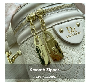 Detail view of smooth golden dual-zippers on beige lychee leather cylindrical bag