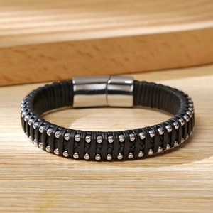 Detail of hand-woven black microfiber leather bracelet with silver bead rivets and metal clasp