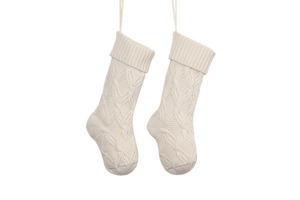 Detail of two white knitted Christmas stockings with cable stitch texture and hanging loops