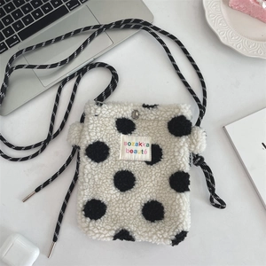 Detail of white plush crossbody bag with black polka dots and rope shoulder strap