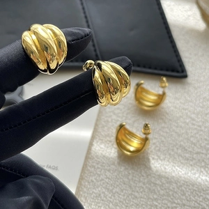 Detailed macro view of triple-layered C-shaped gold hoop earrings with ribbed texture