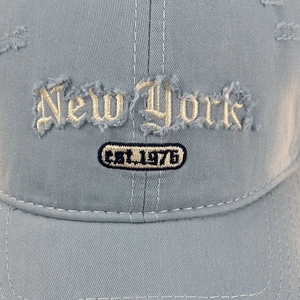 Detail der New York Patch-Stickerei und der Distressed-Fransen an einer blauen Baseballkappe