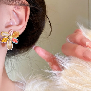 Detailed close-up of a vibrant crystal flower earring worn on an ear with soft background