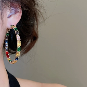 Close-up of gold hoop earrings featuring multi-color rectangular zircon stones