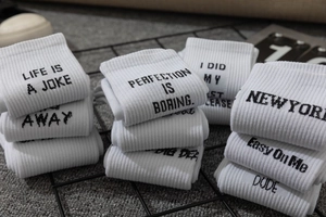 Macro detail of white ribbed crew socks with black letter print on metal grid