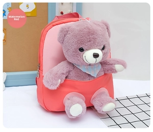 Close-up of watermelon red kids backpack featuring a 3D plush teddy bear and scarf