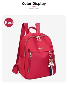 Detail of red oxford backpack showing smooth zipper, metal logo, and teddy bear charm