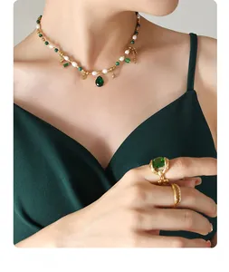 Detail view of pearl necklace with emerald green stone pendant and matching rings set