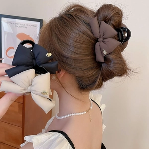 Detail of bow-knot hair claw clips in black, brown and cream on a model's hair