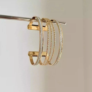Detail view of a multi-layer gold-plated open bangle with textured and polished finishes