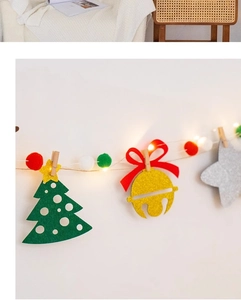 Close-up of Christmas felt banners with green trees, golden bells and warm LED string lights
