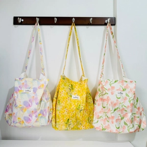 Detailed view of lightweight canvas shoulder bags with floral and butterfly patterns