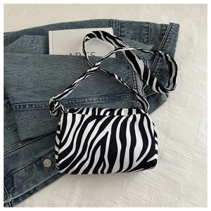 Detail shot of zebra print crossbody bag on blue denim jacket highlighting fabric texture
