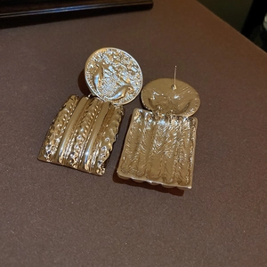 Detailed view of vintage gold-tone earrings with embossed round top and wavy rectangular drop