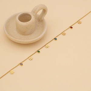 Detailed shot of golden chain necklace with colorful teardrop gems and small flower charms