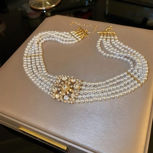Dettaglio del girocollo a 5 file di perle con fiore di strass dorati su portagioie champagne