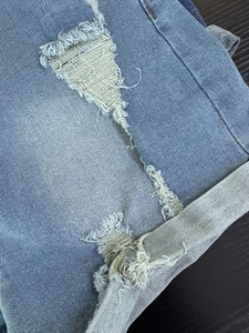 Primer plano de pantalones cortos vaqueros azules con detalles rotos y dobladillo vuelto