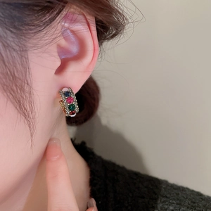 Close-up of gold hoop earrings with multi-colored crystals worn by a model