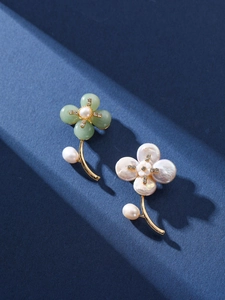 Detail of floral brooches featuring baroque pearls, jade-like petals, and gold metal stems
