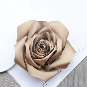 Close-up of champagne gold satin rose brooch with realistic layered fabric petals