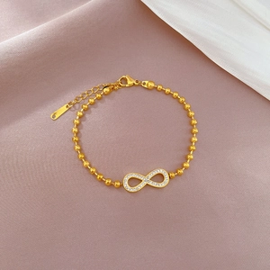 Detail of infinity charm bracelet with white zircons and gold-plated titanium steel beads