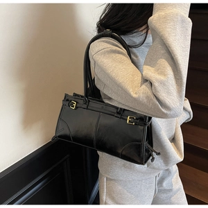 Detail view of the black PU leather handbag with fixed handles and metallic buckles