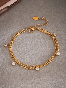 Detailaufnahme einer zweilagigen goldenen Edelstahl-Fußkette mit fünf funkelnden Zirkonia