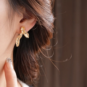 Close-up of golden irregular orchid petal stud earrings with hammered metal texture