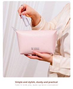 Pink PU leather makeup bag with LOVE print held by a model for a stylish travel look