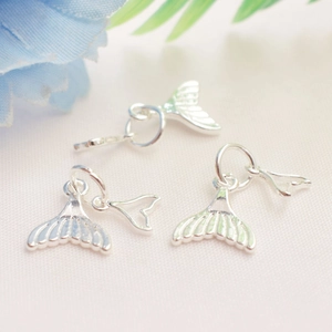 Vue macro de breloques queue de poisson argentées avec texture rayée pour bijoux DIY