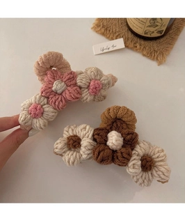 Detailed macro view of handmade crochet flower hair claws in pink and beige wool yarn