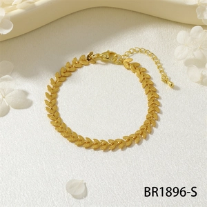 Dettaglio del bracciale dorato con maglie a V e chiusura a moschettone su tessuto bianco