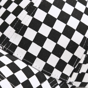 Dettaglio macro del motivo a scacchi bianco e nero con cuciture precise sul cappellino da baseball