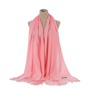 Close-up of pink cashmere scarf with fringe tassels on beige mannequin torso