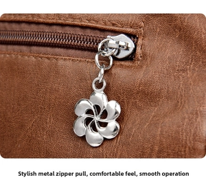 Detail of silver flower-shaped zipper pull on brown lychee grain leather handbag