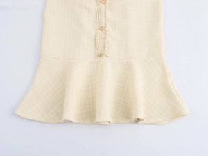 Close-up of beige tweed mermaid dress hem with textured fabric and button details
